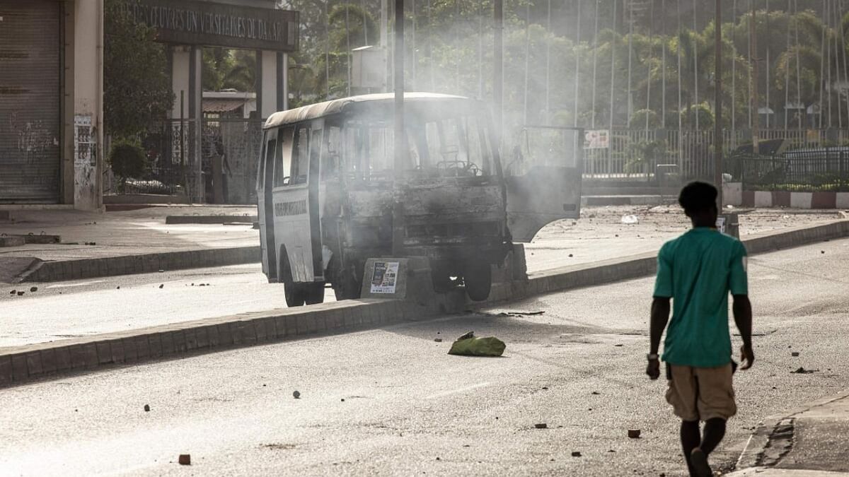 A man walks past a burned bus, attakcked in Dakar, on June 1, 2023 during a protest. A court in Senegal on Thursday sentenced opposition leader Ousmane Sonko. Credit: AFP Photo