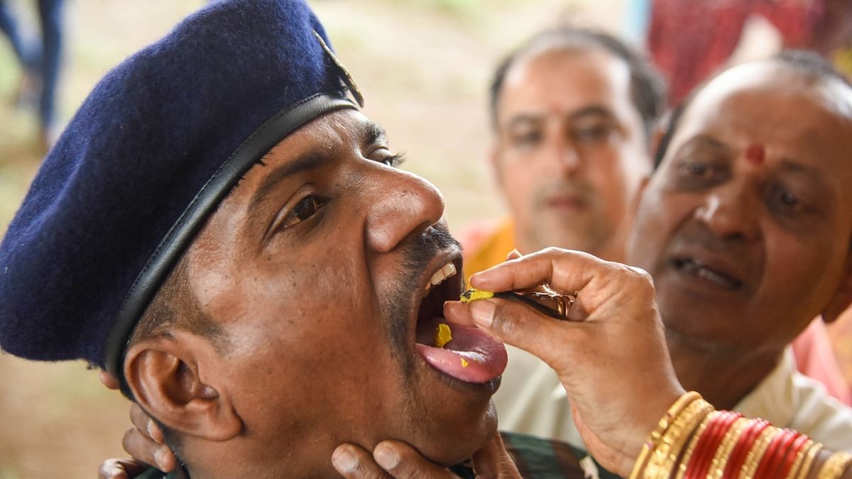 An Army jawan receives traditional fish 'prasadam' from a member of the Bathini family to get relief from respiratory problems at the Nampally Exhibition ground in Hyderabad. Credit: PTI Photo