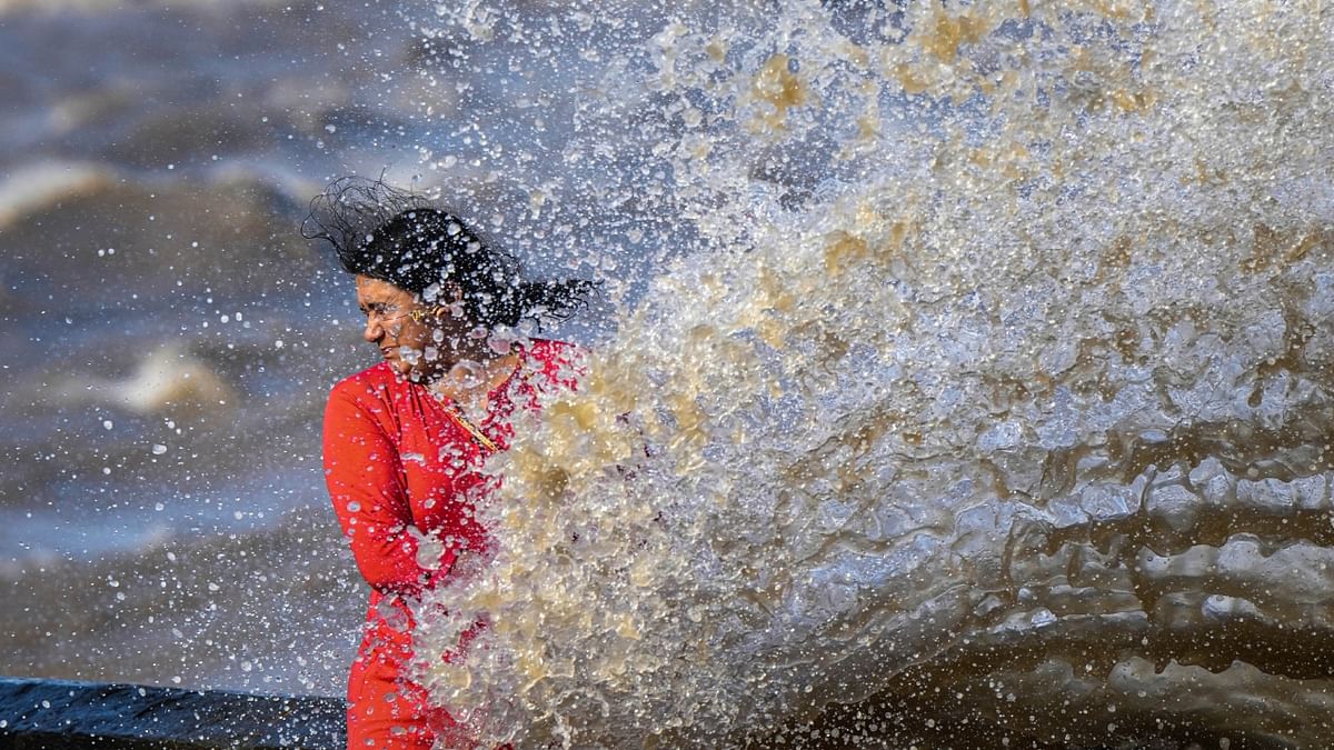 A woman reacts as high sea waves crash at the Gateway of India, in Mumbai. Credit: PTI Photo