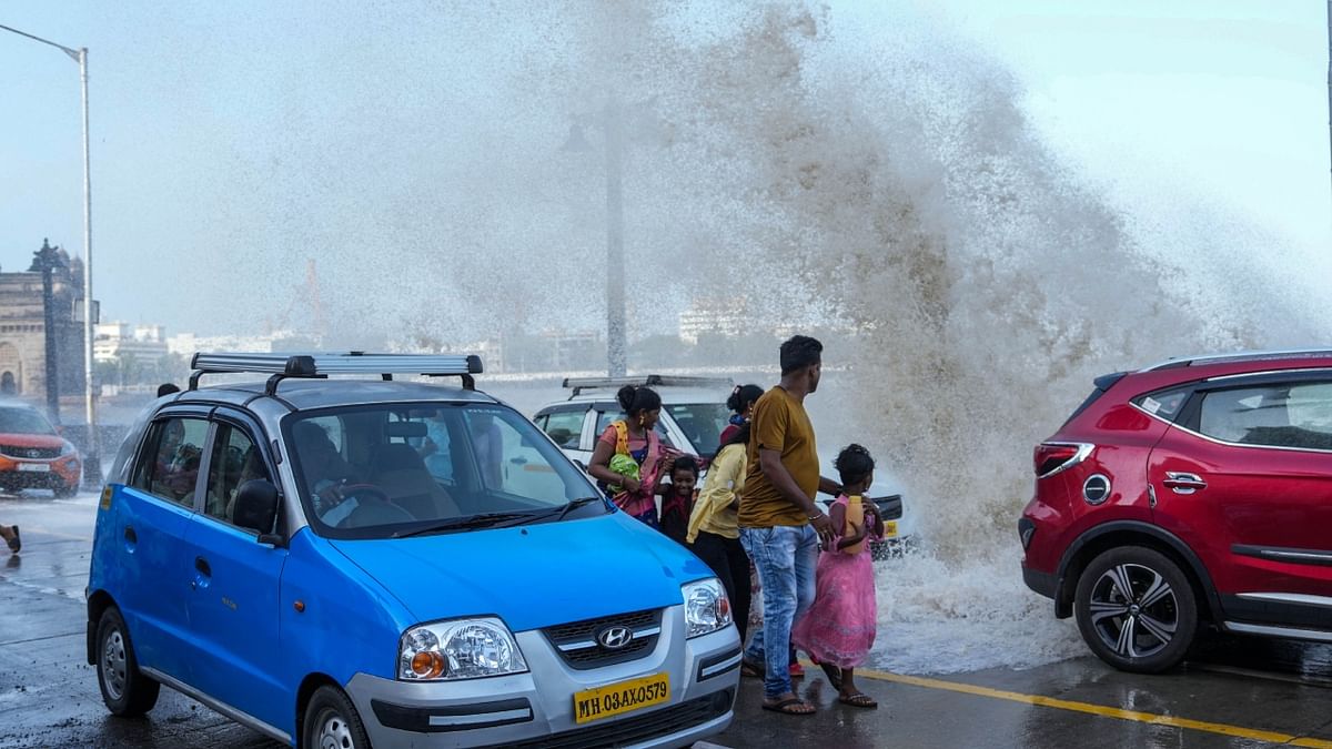 People move as high sea waves crashes near the Gateway of India, in Mumbai. Credit: PTI Photo