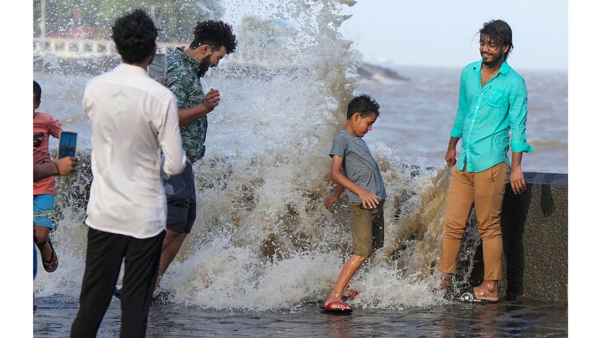 People play in the high sea waves crashing near the Gateway of India, in Mumbai. Credit: PTI Photo