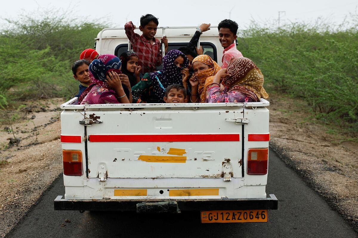 A family leaves a village in the back of a pickup truck before the arrival of cyclone Biparjoy in Jakhau, Gujarat. redit: reuters Photo