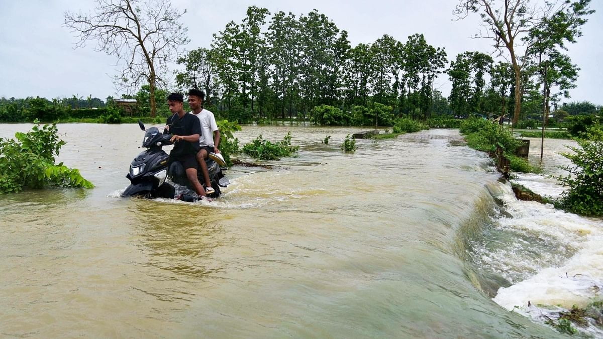A man rides his two-wheeler as he wades through a flooded road following a heavy rain in Kampur, Nagaon District of Assam. Credit: IANS Photo