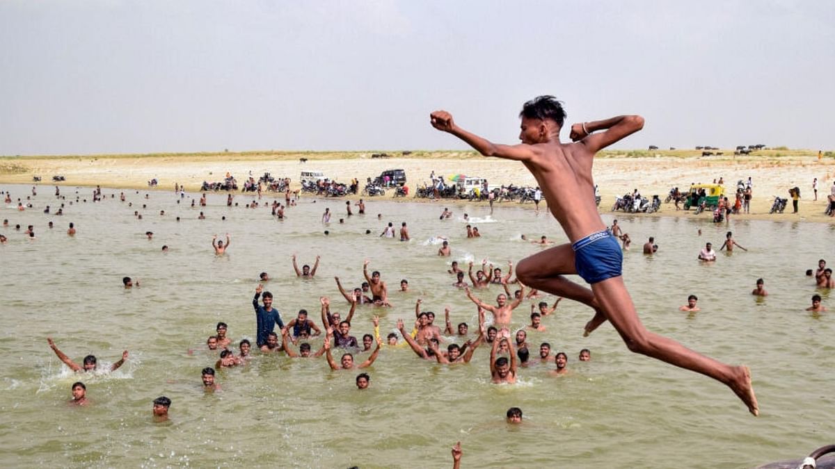 A young man dives into Rapti River as people enjoy at the river bank on a hot summer day, in Gorakhpur, Monday, June 19, 2023. Credit: PTI Photo