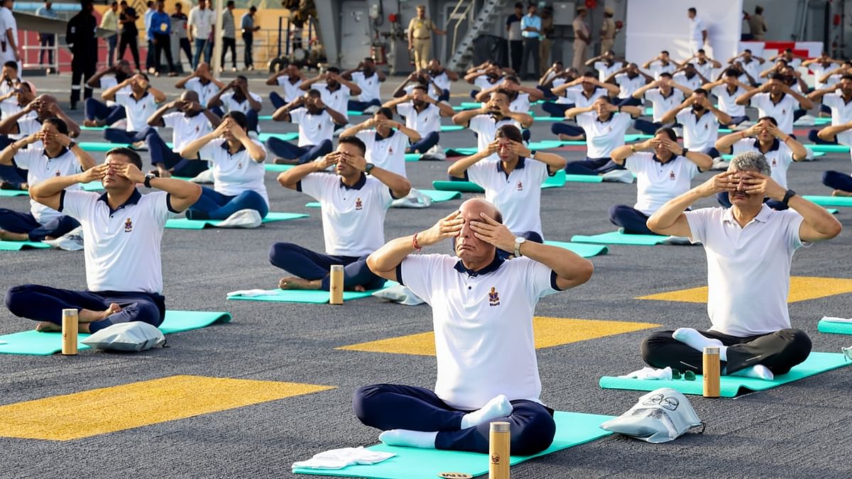 Defence Minister Rajnath Singh and others performs yoga on the International Day of Yoga onboard INS Vikrant, in Kochi. Credit: PTI Photo