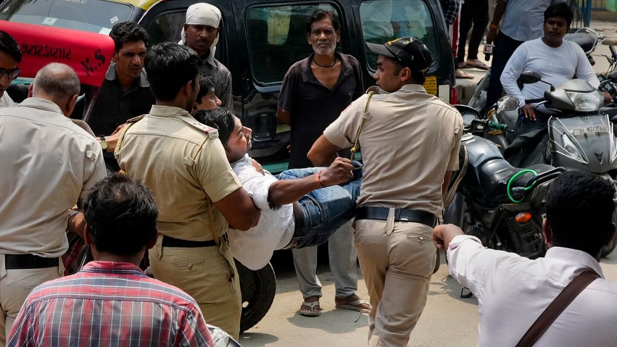 Police personnel detain locals protesting against the removal of a portion of a temple in Mandawali area of New Delhi. Credit: PTI Photo