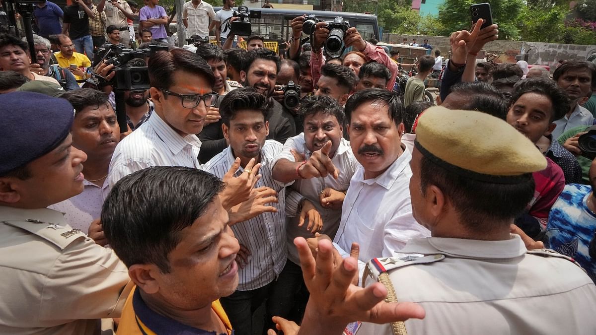 Police personnel interacts with locals protesting against the removal of a portion of a temple in Mandawali area of New Delhi. Credit: PTI Photo