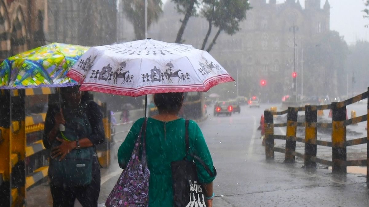 Commuters hold umbrellas as they walk on street amid heavy rain, at CST road, in Mumbai. Credit: IANS Photo