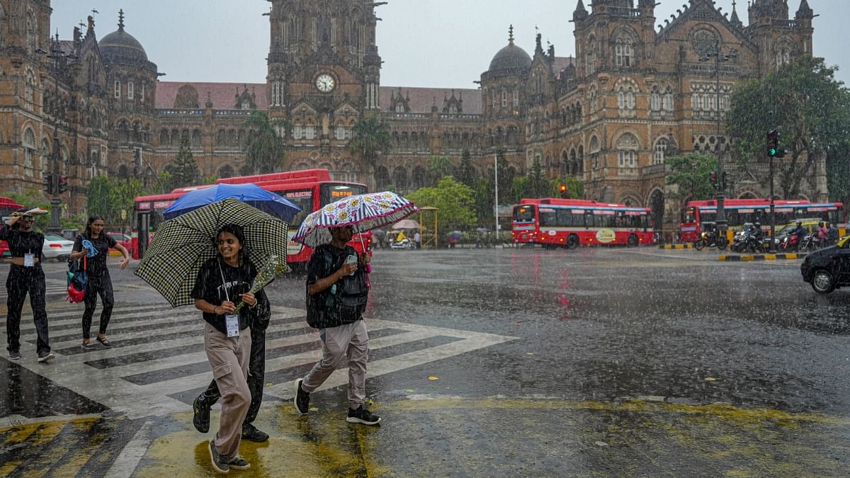 Pedestrians cross road during rain, at Chhatrapati Shivaji Maharaj Terminus, in Mumbai. Credit: PTI Photo
