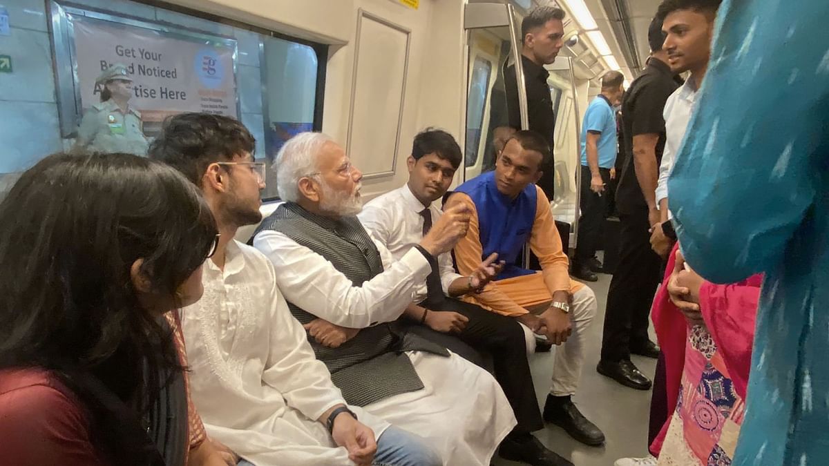 PM Modi interacts with passengers as he travels on Delhi Metro to reach Delhi University to attend its centenary celebrations. Credit: PTI Photo