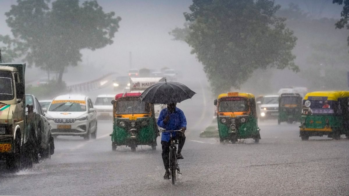 Commuters move past during monsoon rain, in New Delhi. Credit: PTI Photo