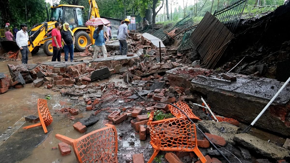 Locals and officials near a collapsed wall after monsoon rain at Sundar Nagar, in New Delhi. Credit: PTI Photo