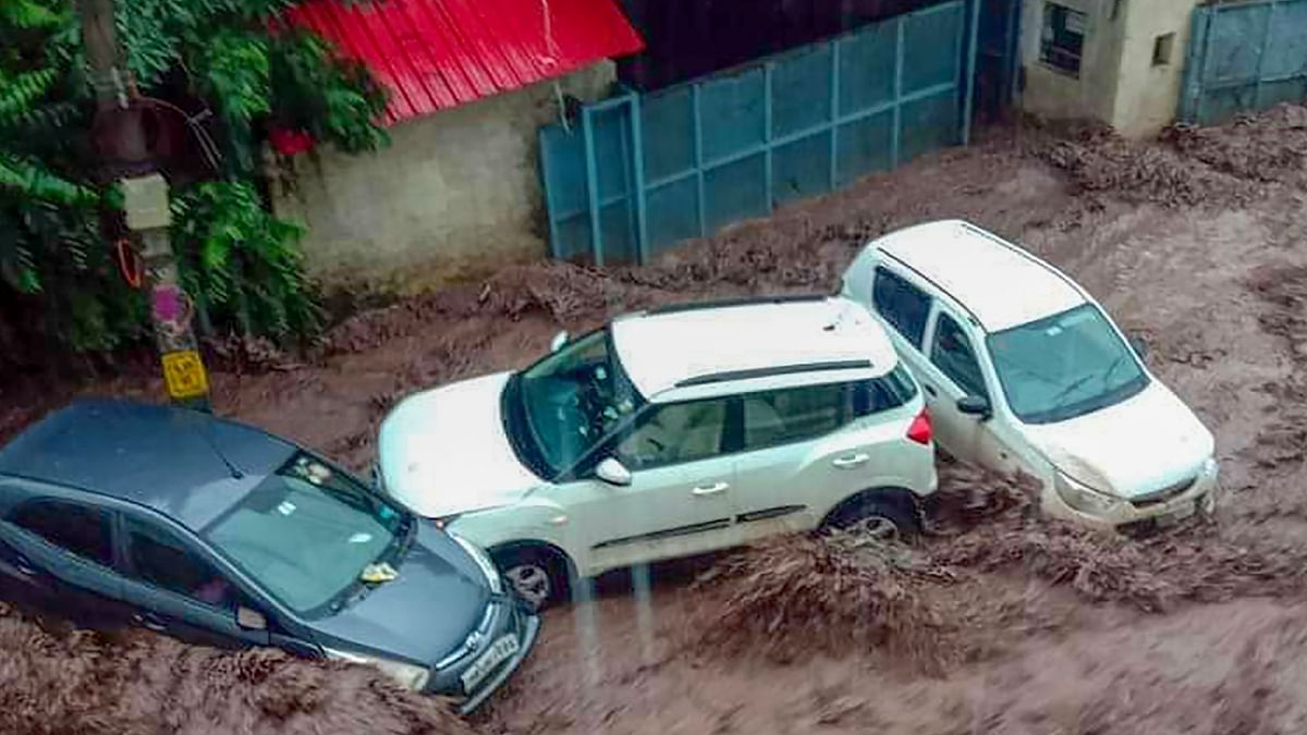 Vehicles being swept away during flash floods amid heavy monsoon rainfall at Parwanoo, in Solan. Credit: PTI Photo