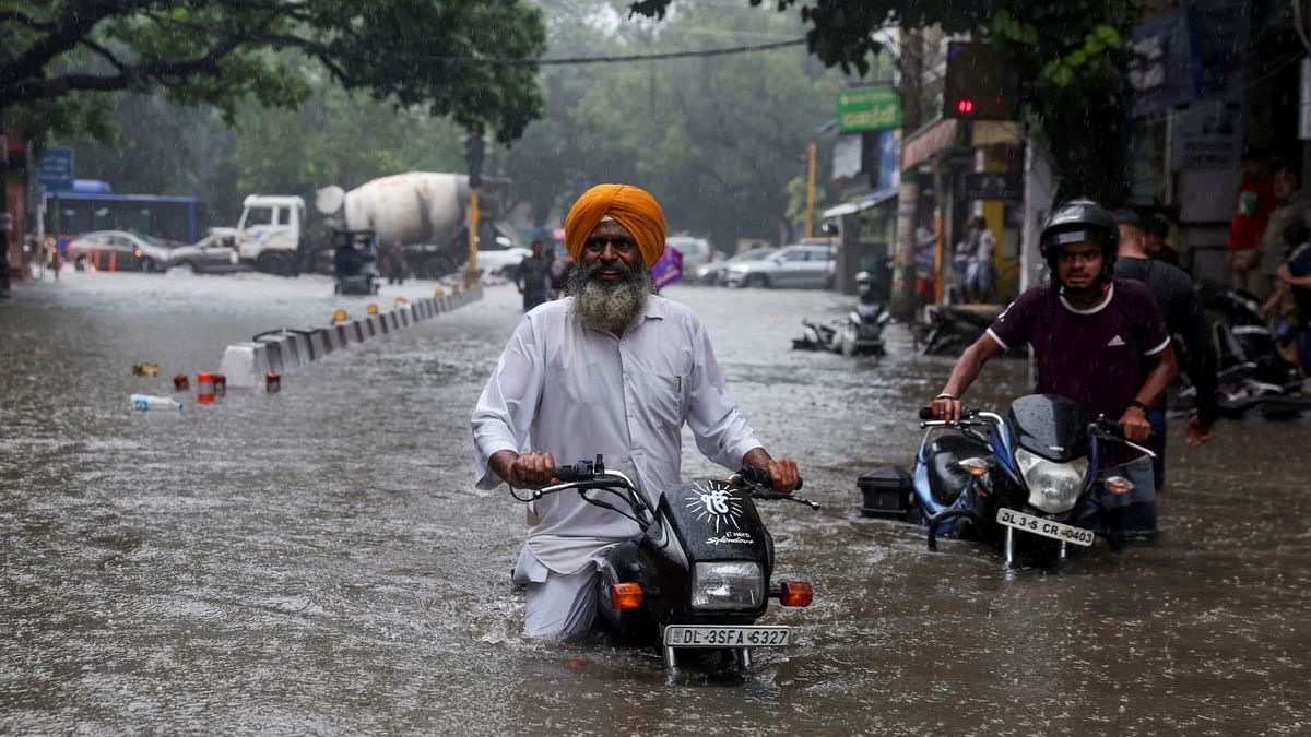 A man on his motorbike wades through a flooded street after heavy rains in New Delhi. Credit: Reuters Photo
