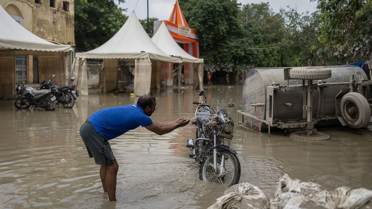 A man cleans his bike as the flood water start to recede. Credit: Reuters Photo