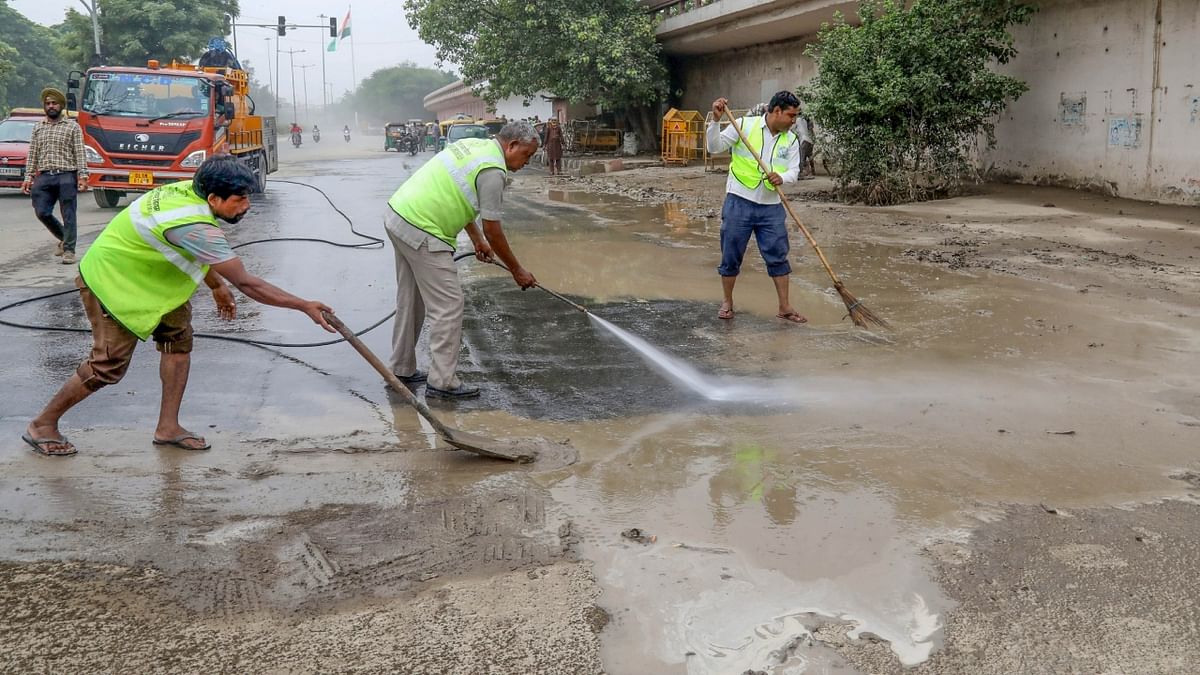 Municipal Corporation of Delhi workers clean the road near the monastery market after Yamuna floodwater receded in New Delhi. Credit: PTI Photo