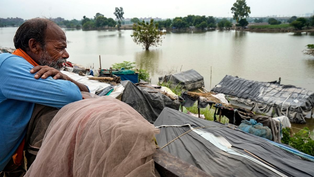 A flood-hit resident looks at houses submerged in the floodwaters of the swollen Yamuna river near Nizamuddin Bridge, in New Delhi. Credit: PTI Photo