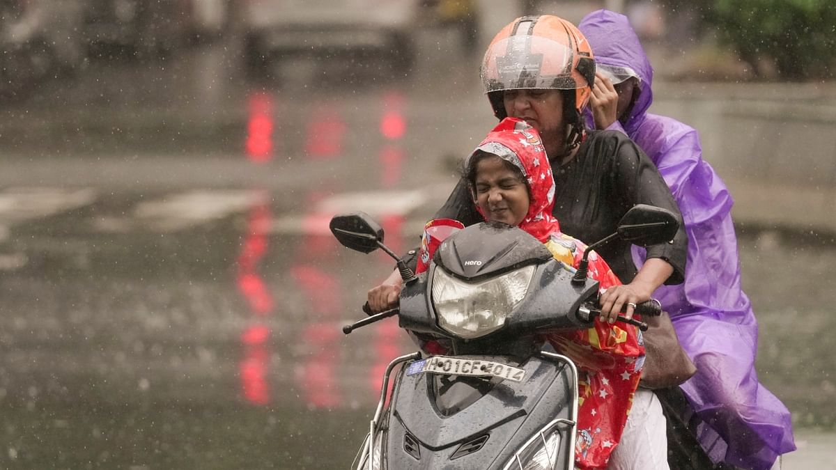 Commuters riding through rain in Mumbai. Credit: PTI Photo