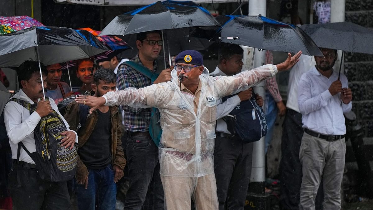 A traffic police personnel manages traffic during monsoon rains in Mumbai. Credit: PTI Photo