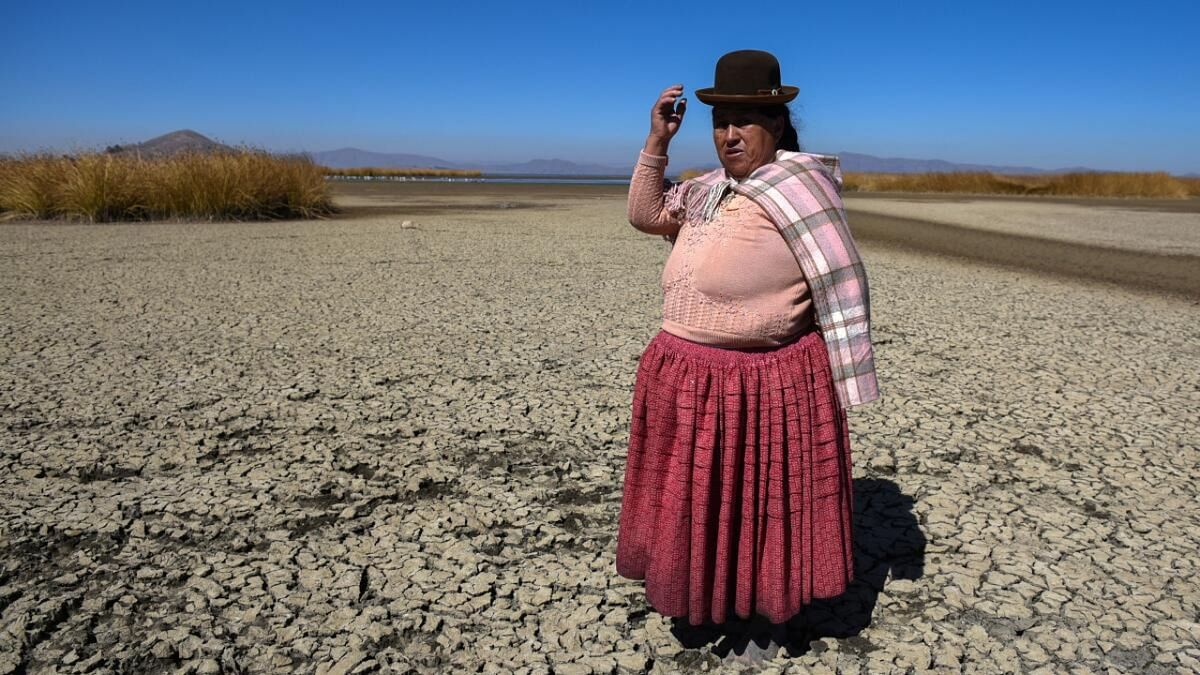 Isabel Apaza shows the area of Lake Titicaca without water in drought season, in Huarina, Bolivia. Credit: Reuters Photo