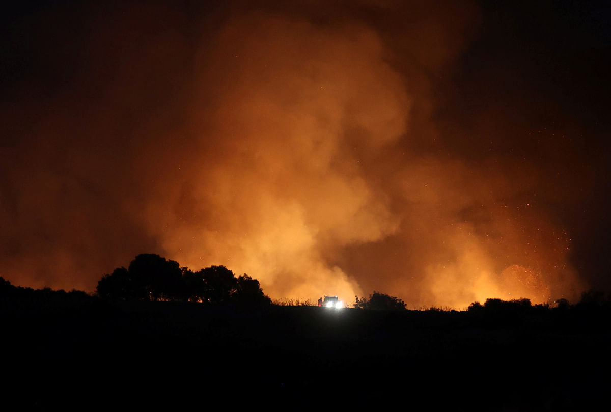 A person is silhouetted in front of a wildfire near the village of Alassa, Cyprus. Credit: Reuters Photo
