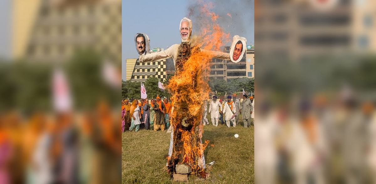 Farmers gather as they burn effigies of India's Prime Minister Narendra Modi (C), Chairman of Reliance Industries Ltd company Mukesh Ambani (R), and Chairman and Founder of the Adani Group Gautam Adani, to protest against corporate businesses following the recent passing of agriculture bills in the Parliament, during a demonstration in Amritsar. Credit: AFP