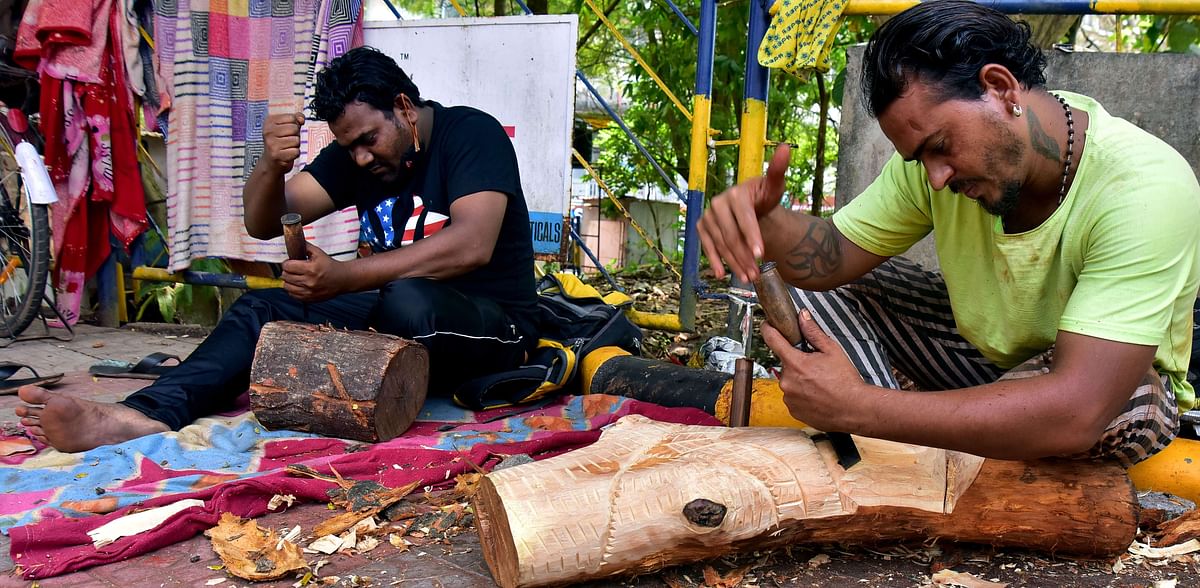 Artists Ravi Bhat and Vikram Bhat work on a piece of wood at the pavement in Lalbagh in Mangaluru. DH Photos/Govindraj Javali