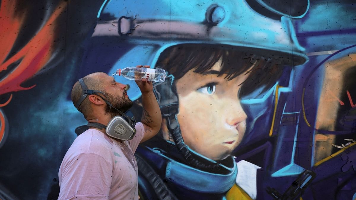 Davide Pianta, a graffiti artist from Italy, freshes himself with water in front of his mural as part of the Meeting of Styles graffiti festival in Kosovo's capital Pristina, Kosovo July 29, 2023. Credit: Reuters Photo