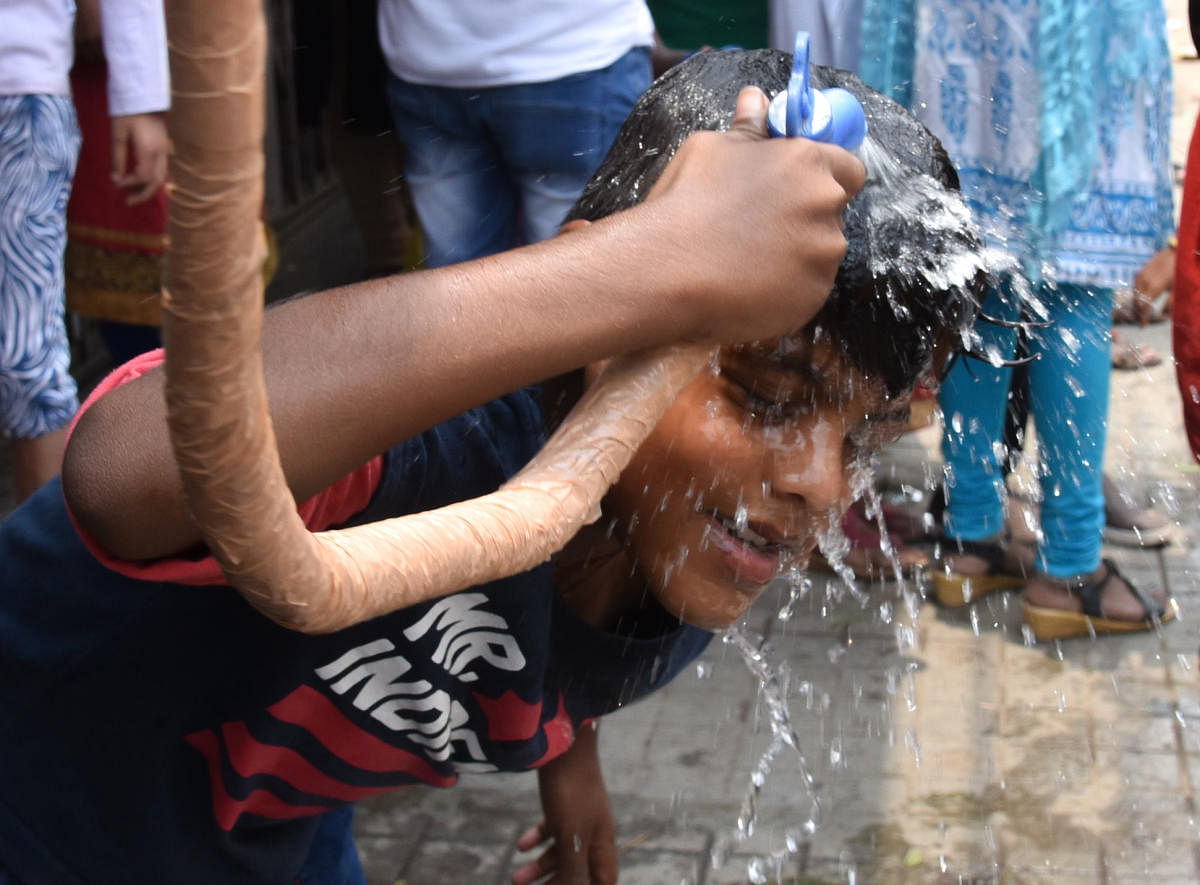A boy watering on the head to beat the heat at Halasuru in Bengaluru on Sunday. Photo by S K Dinesh