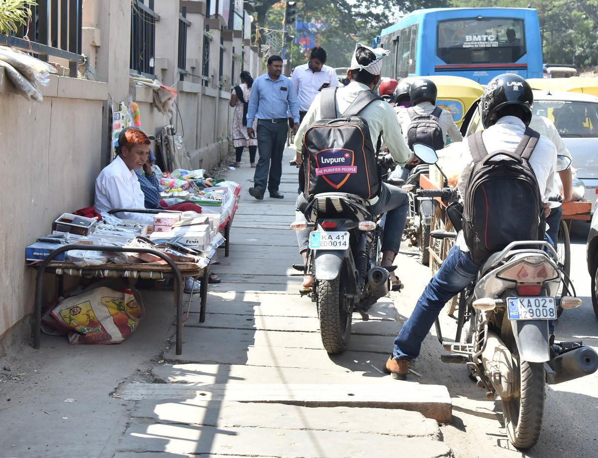 Pedestrians suffer when two-wheeler riders ride on the footpath and also due to vendors' encroachment. A scene on the road leading from Manipal hospital to Kemp Fort on Old Airport Road.
