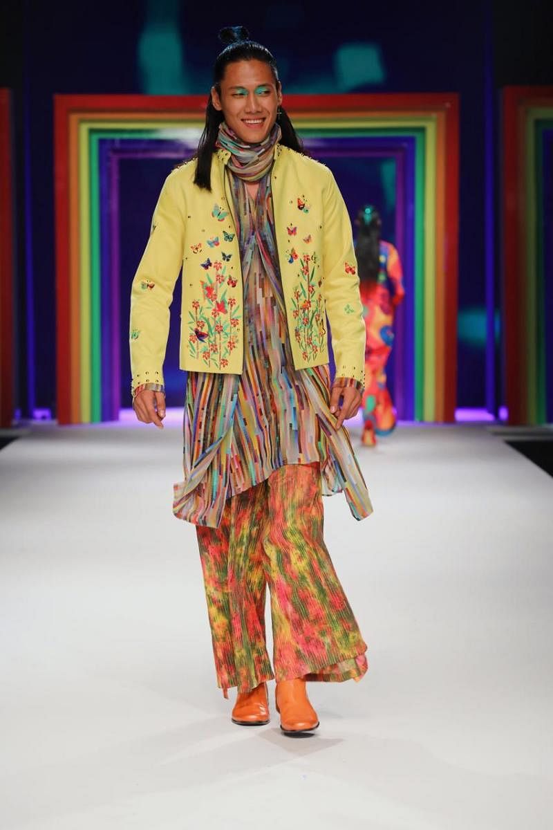 Yellow suede bomber jacket with flower and butterfly embroidery and gold rivets, worn with rainbow colour viscose stole kurta and tie-and-dyed pintucked cotton wrap around pants and orange leather boots. 