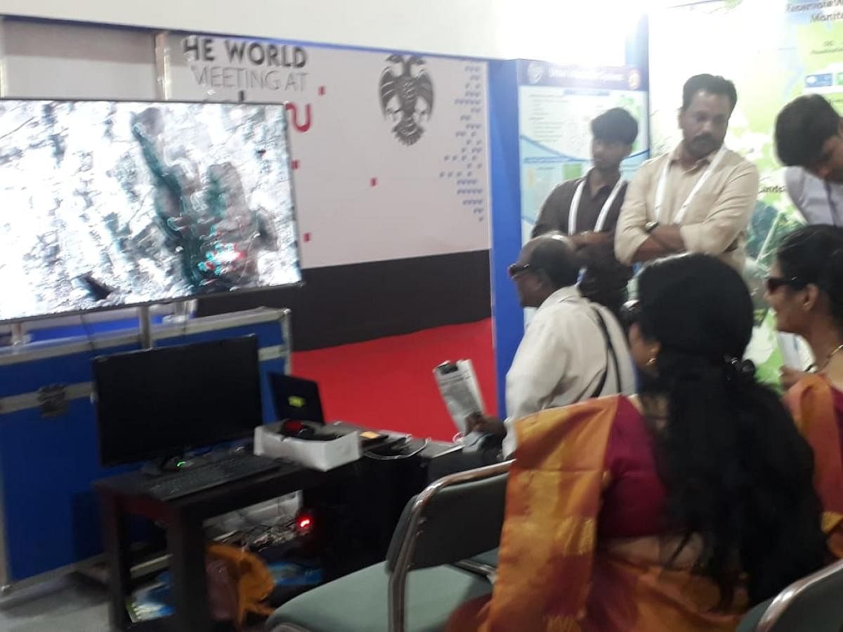 People use 3-D glasess to observe a map on display at the Karnataka state remote sensing application centre's booth.