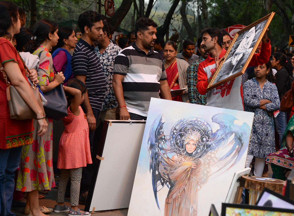 Visitors view artworks displayed during the Chitra Santhe organised at the Karnataka Chitrakala Parishath on Sunday. DH photo/Satish Badiger