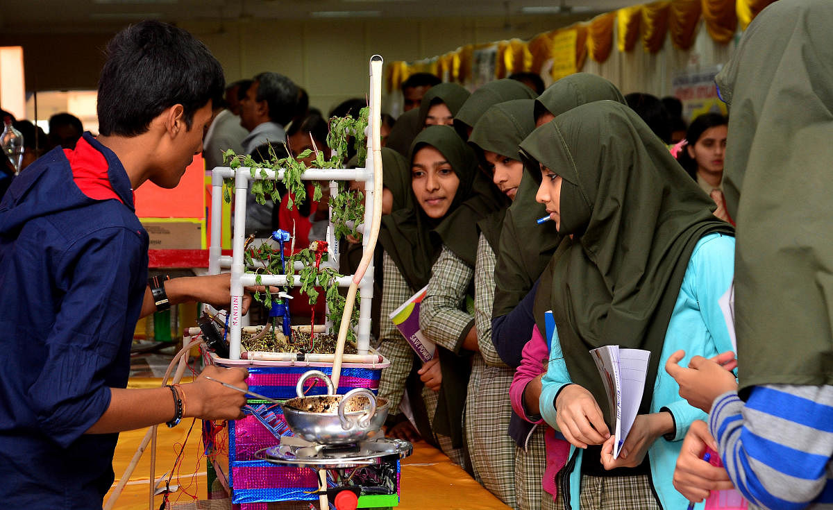 Students look at models displayed in the science fair.