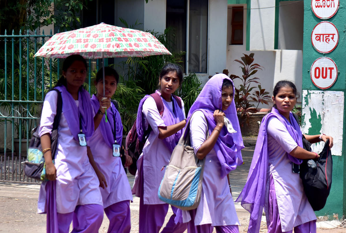 Young girls use dupattas, umbreallas whatever handy to shield themselves from the scorching sun on Monday. –Photo/ Govindraj Javali