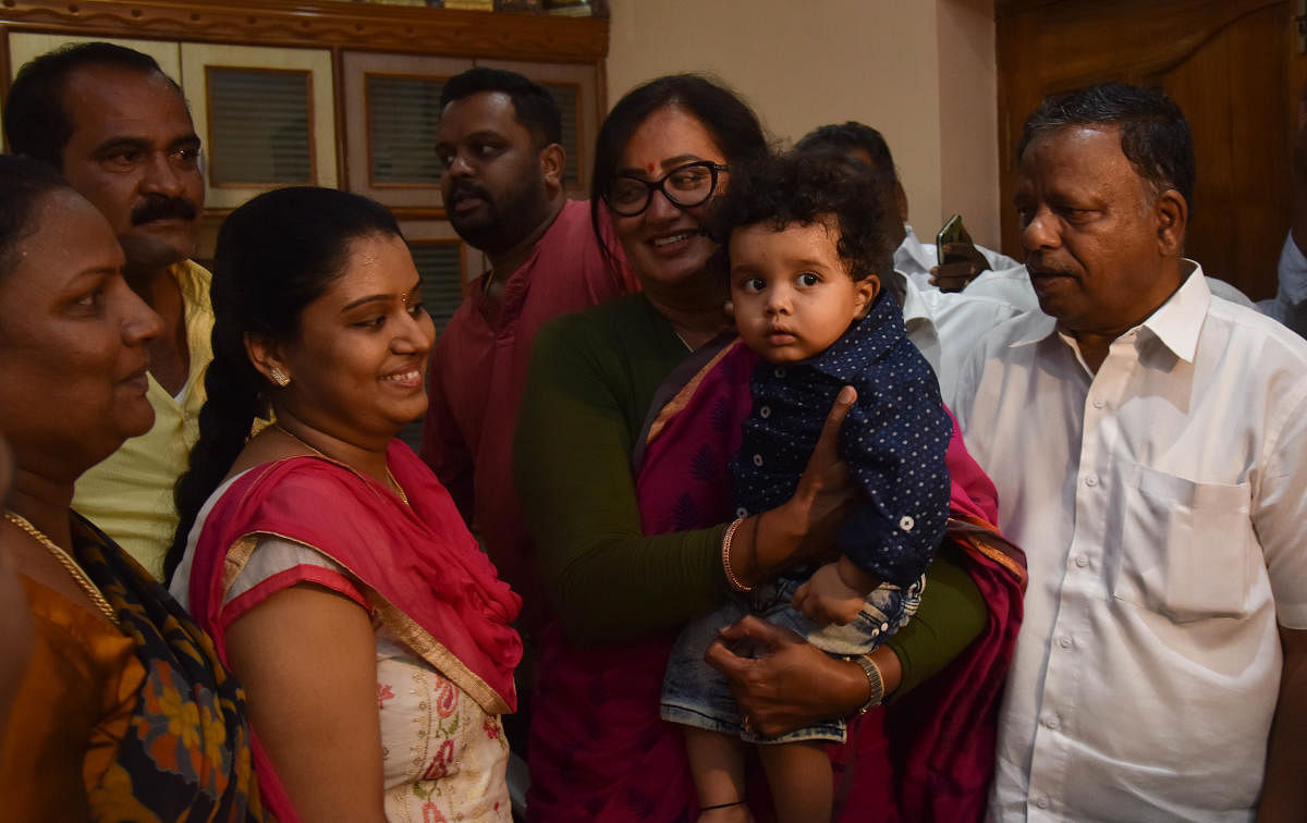 Independent candidate Sumalatha Ambareesh bonds with a family at KR Pet in Mandya district on Thursday. (Right) Coalition candidate for Mandya seat Nikhil Kumaraswamy gels with voters at B Gowdagere and Kannalli in Mandya district on Thursday. DH Photos /