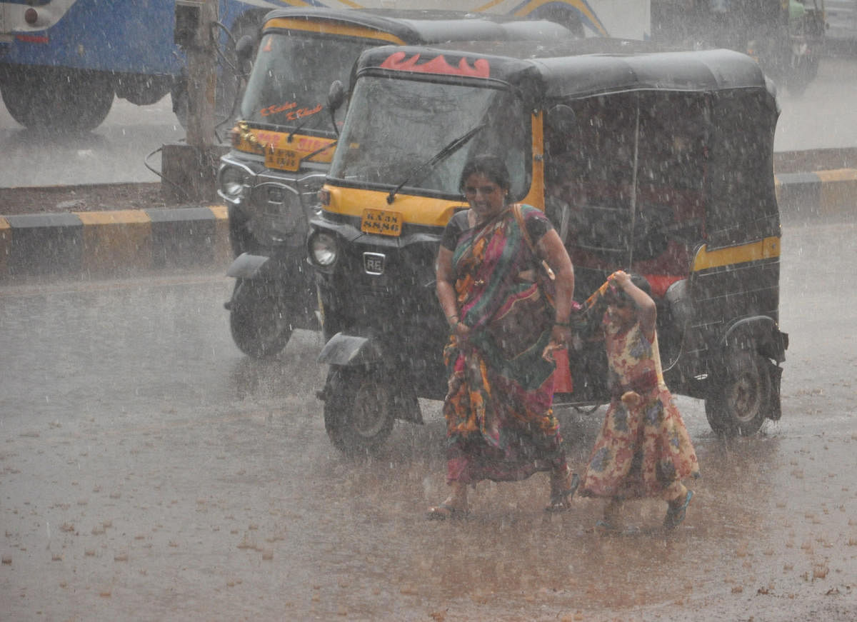 A woman and her daughter find it tough to walk on the road at Janwad in Bidar as it rains heavily. DH Photo