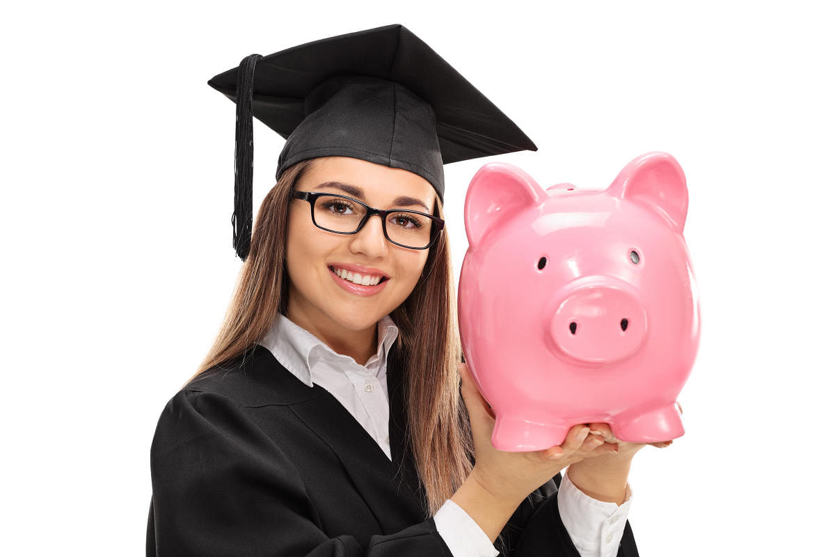 Happy graduate student holding a piggybank isolated on white backgroundStudent education Loan