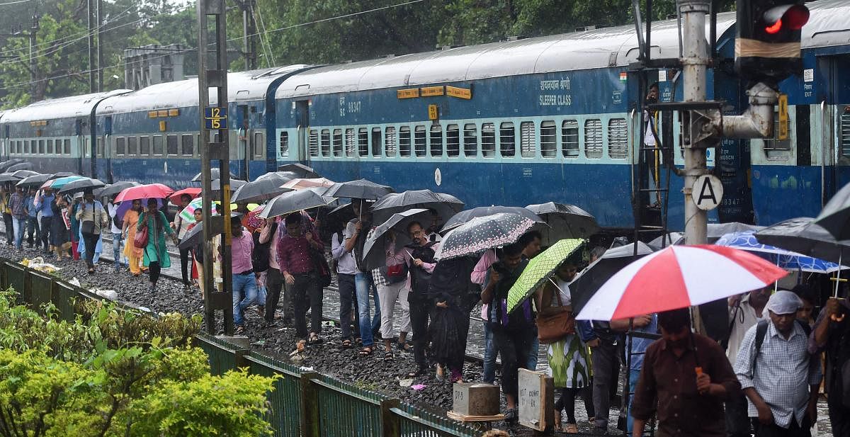 People walk on the railway tracks as heavy monsoon rains hit the local train services, in Mumbai. (PTI Photo)