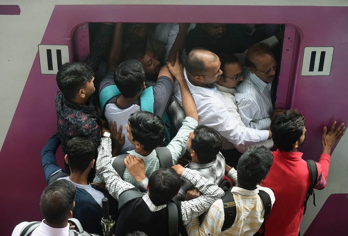 Indian passengers try to enter into a crowded local train compartment in Mumbai on July 5, 2019. (Photo: AFP)