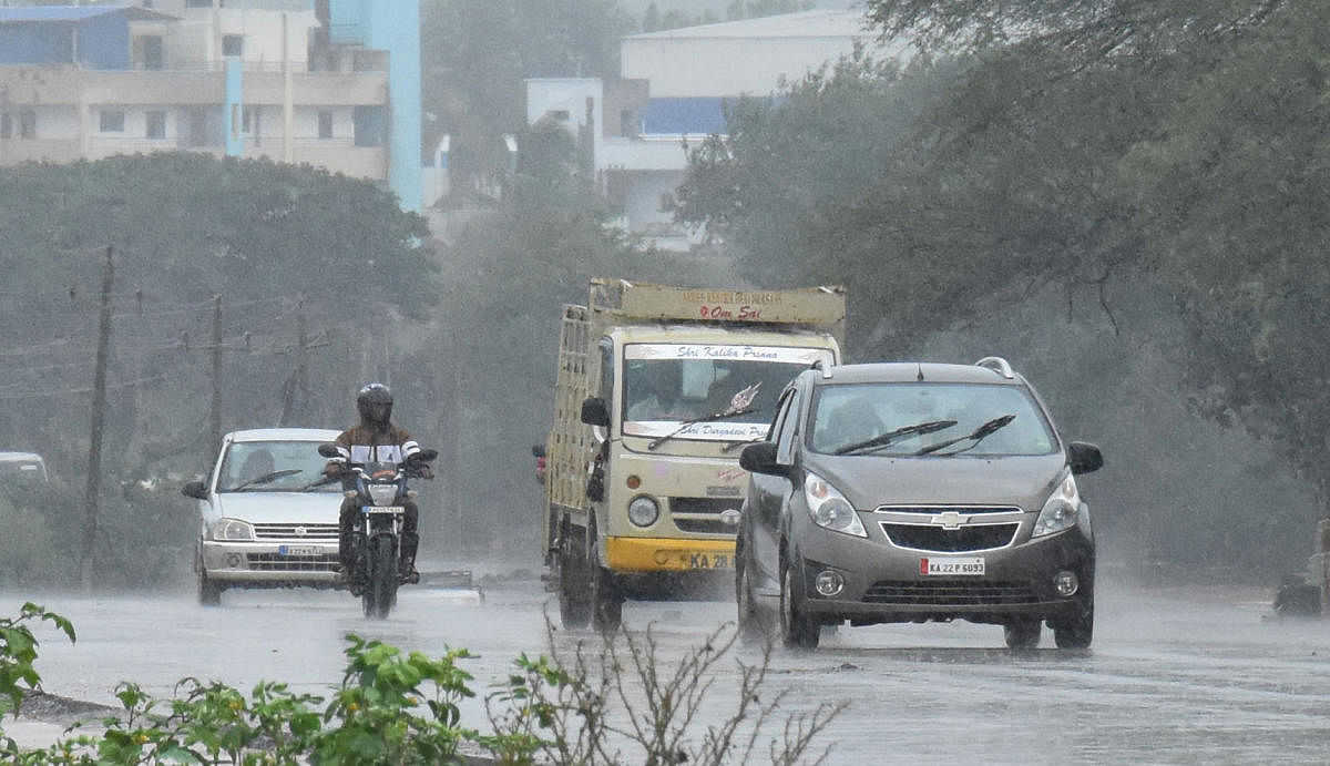 Motorists brave the showers in Dharwad city on Sunday.