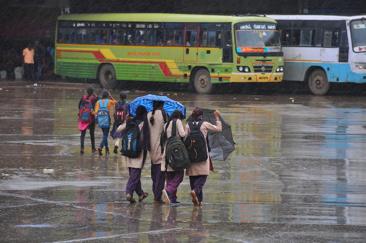 Students scurry for cover as light showers lashed Haveri town through the day on Wednesday. DH photo