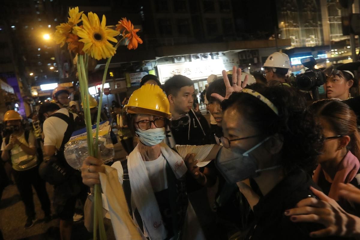 A protester holds flowers after a march against a controversial extradition bill in Hong Kong on July 21, 2019. (Photo by AFP)