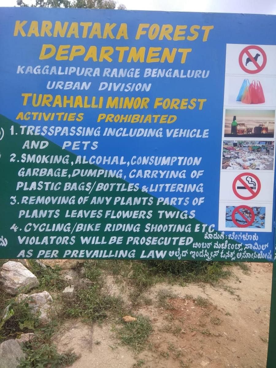 A notice board warns against trespassing on the Turahalli reserve forest. 