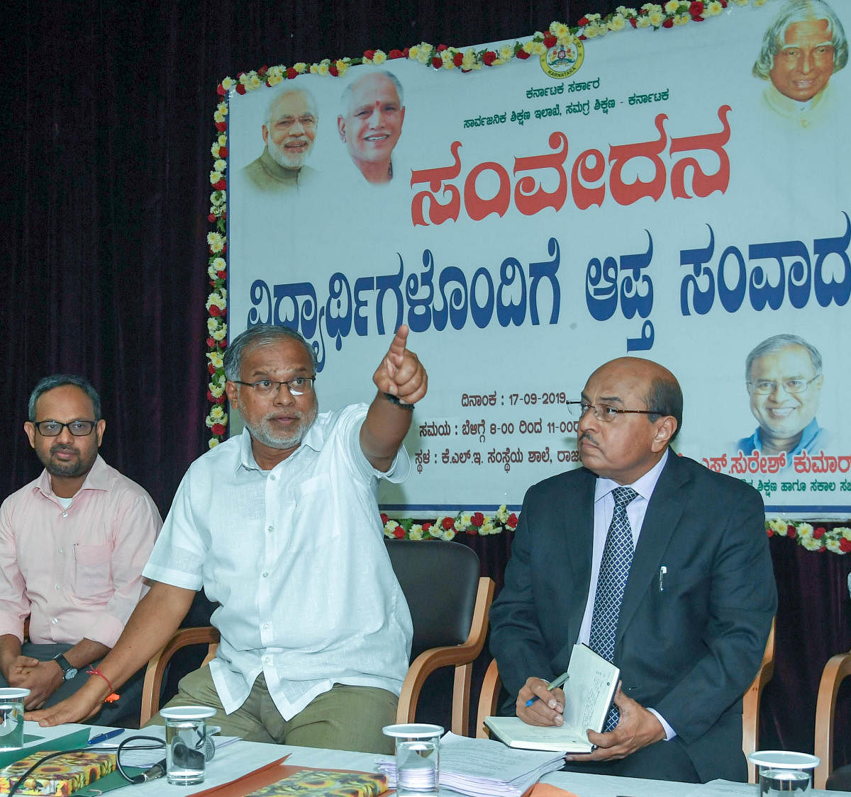 The minister gestures at the programme. Educationist Gururaj Karajagi (extreme right) is also seen.