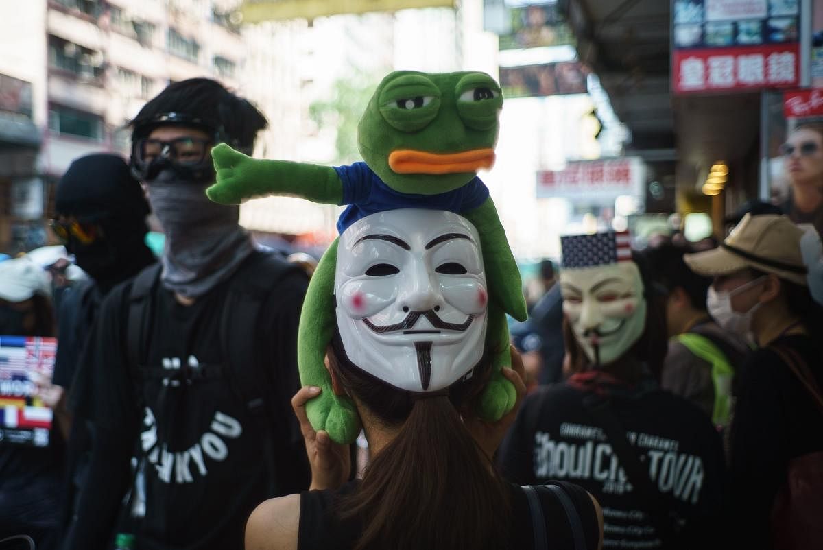 A protester holds a Pepe the Frog stuffed toy above a Guy Fawkes mask on the back of her head, popularised by the V For Vendetta comic book film, in Hong Kong. (Photo by AFP)