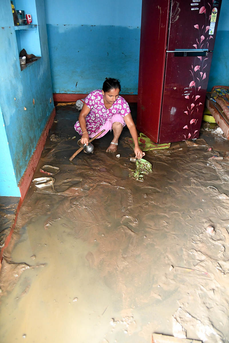 A woman clears the floodwater from home. DH PHOTO/B H SHIVAKUMAR