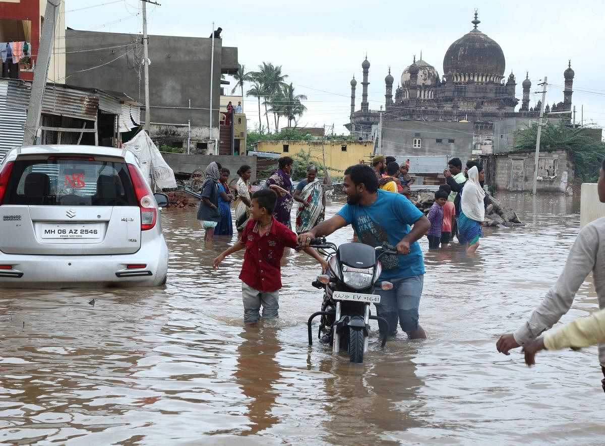 People wade through a flooded road in Vijayapura. The city experienced downpour on Sunday night.