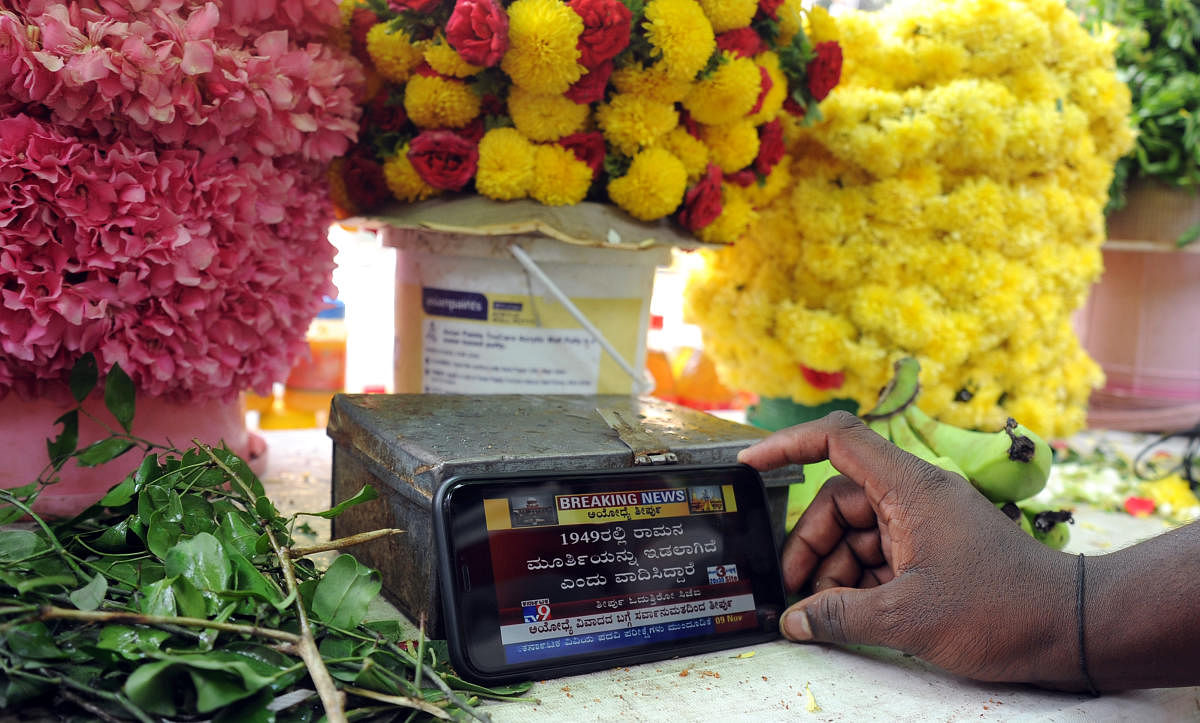 A flower vendor from Malleswaram watches the Ayodhya verdict on his phone. DH PHOTO/PUSHKAR V