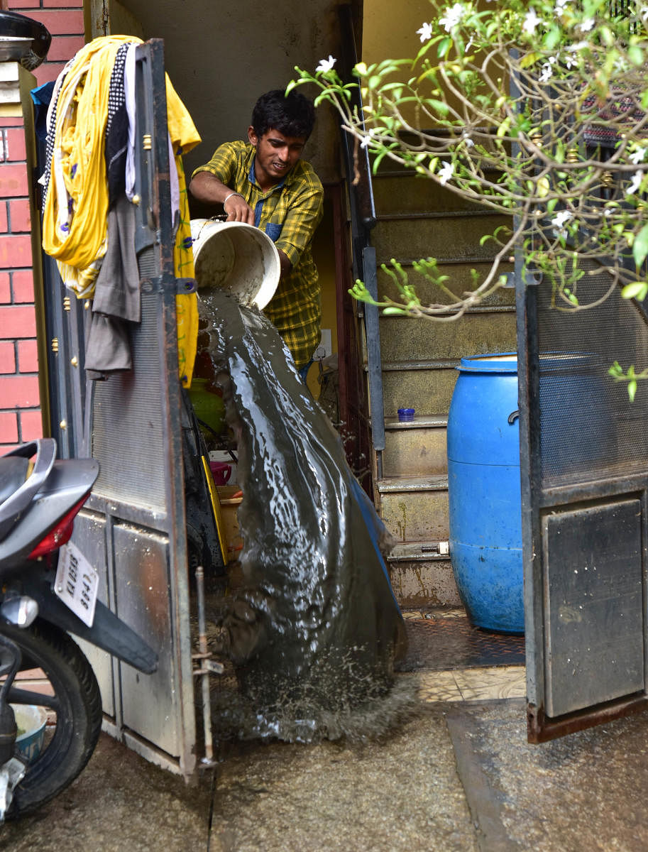 A resident of Pramod Layout throws dirty water out of his home. DH PHOTO/IRSHAD MAHAMMAD